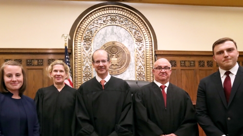 Judges and students standing in courtroom