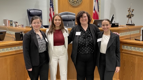 Women standing in courtroom after winning competition