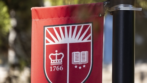 A flag with the Rutgers crest being flown on a pedestrian path on campus.