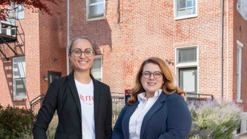 Two women standing and smiling wearing glasses
