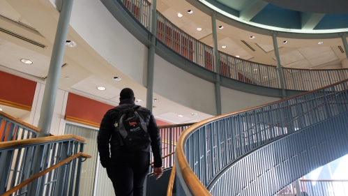 man with backpack walking up spiral staircase