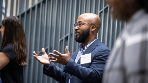A man holds his hands out demonstratively while engaging in a discussion.
