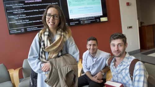 Three students smile while seated in a study lounge.