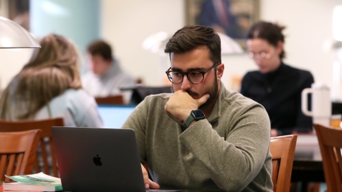 man studying on laptop in library