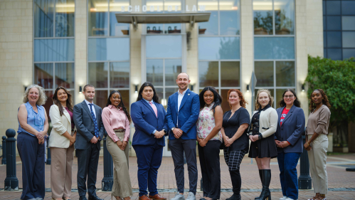 group of men and women standing side by side outside of law building