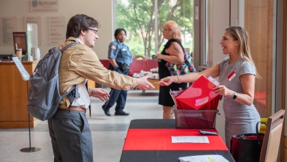 Woman shaking hands with student across table.