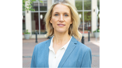 woman in white blouse and light blue blazer standing outside building