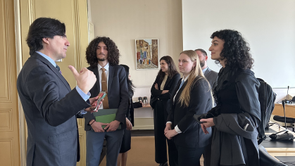 group of men and women standing in business suits listening to man