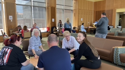 groups of people seated and talking with each other in large wood-paneled room