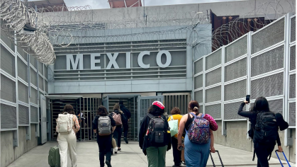 group of people walking toward building with large 'Mexico' sign