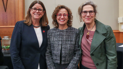 Three women wearing glasses standing next to each other and smiling