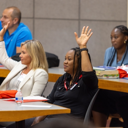 Two women raising their hands in classroom.