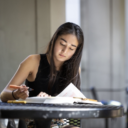 Woman sitting at table and highlighting a book