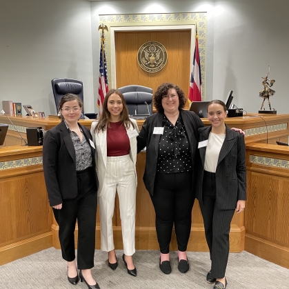 Women standing in courtroom after winning competition