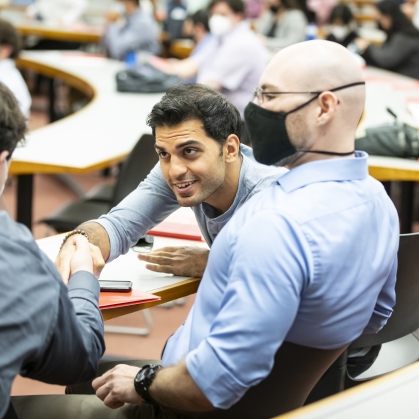 Man shaking another person’s hand in classroom