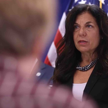 Professor at podium with American flag behind her