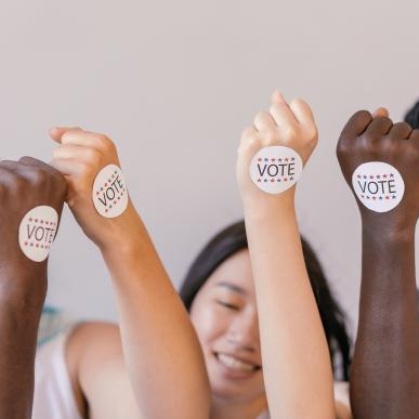 people with fist up that have 'I voted' stickers on them