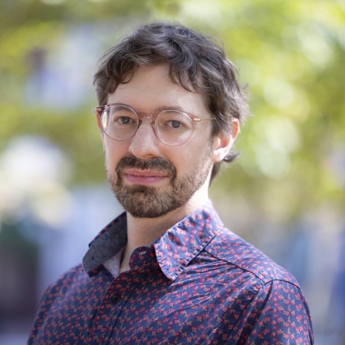 a man with a beard and glasses smiling