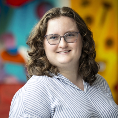 woman wearing glasses and smiling in front of blurred art photo