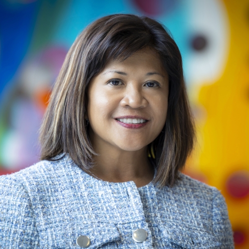 woman smiling in front of blurred art mural