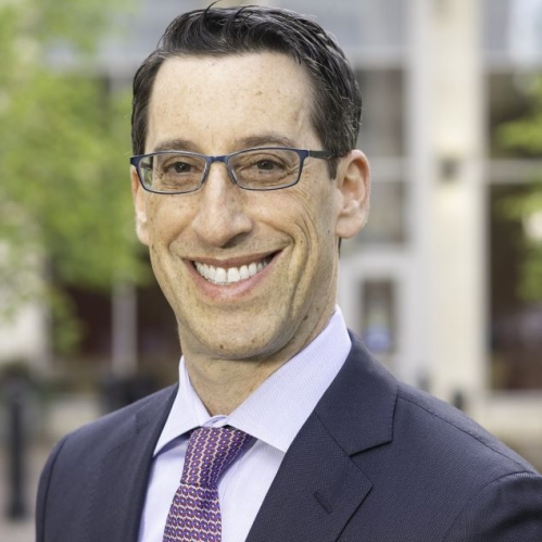 man outside building with tinted glasses smiling