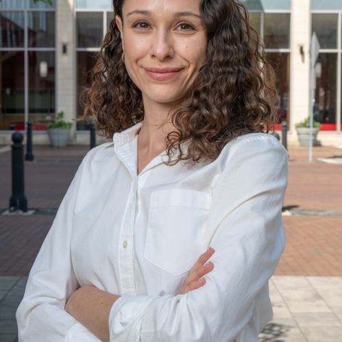 Image of woman with a white shirt and brown hair in front of the School of Law building