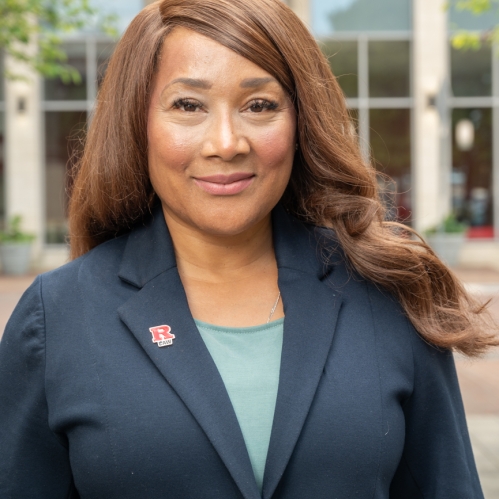 Woman in dark blazer with R Law red pin smiling outside law school