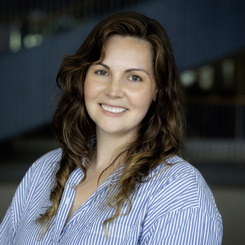Woman smiling wearing blue and white striped button down shirt.