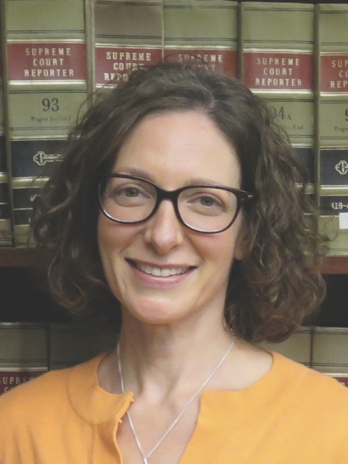 woman smiling in front of book shelf