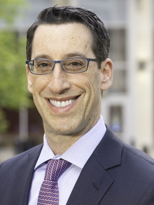 man outside building with tinted glasses smiling 