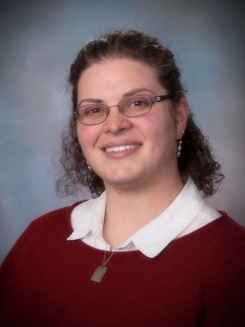 Woman smiling with glasses wearing red sweater and white collared shirt 