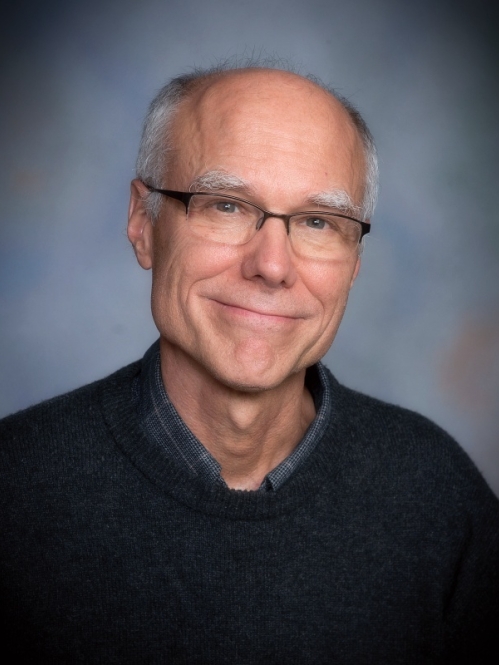 Man grinning with glasses wearing a black sweater 