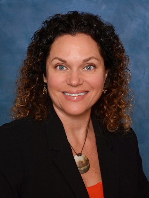 headshot of woman smiling in front of blue backdrop