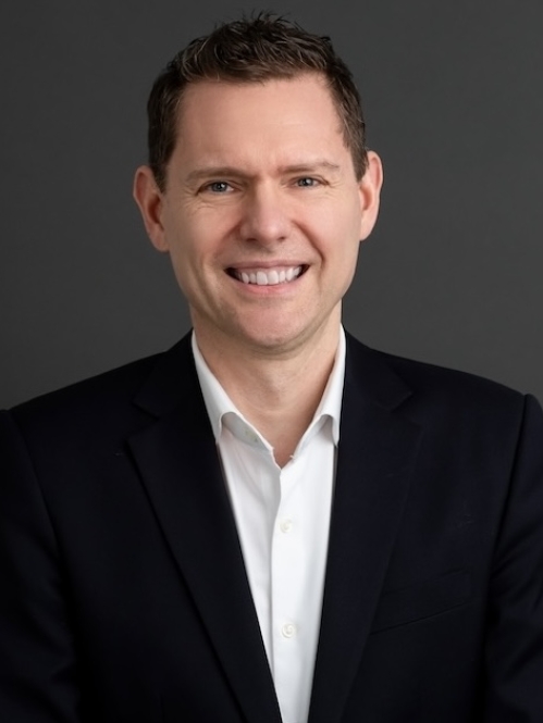 Man in black blazer and white shirt smiling