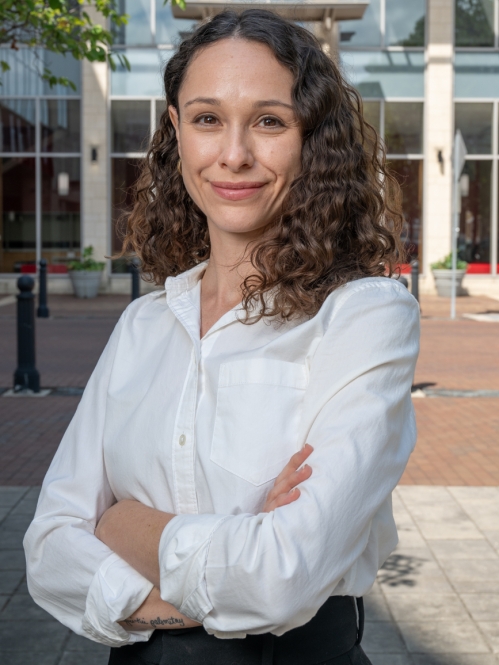 Image of woman with a white shirt and brown hair in front of the School of Law building