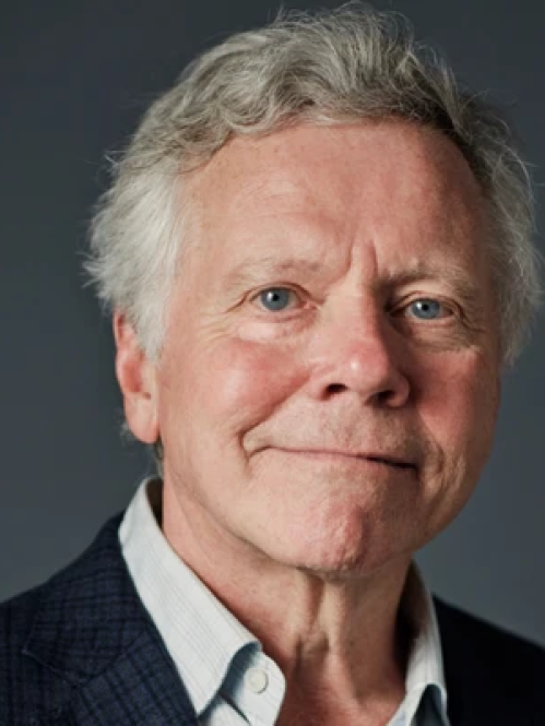 Man with gray hair in blazer and shirt smiling