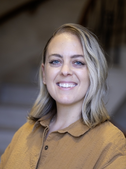 woman smiling wearing gold shirt in front of stairs