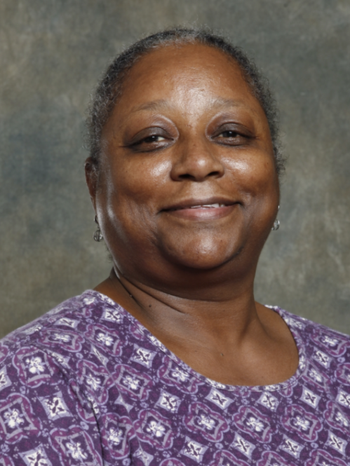 Woman grinning wearing purple patterned shirt. 