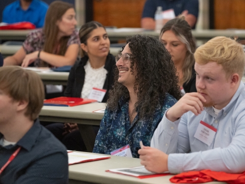 Man with long curly hair smiling in classroom