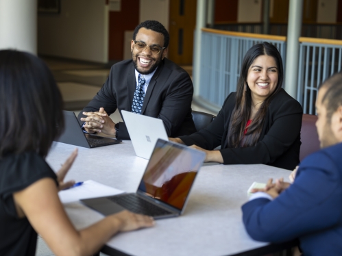A group of Rutgers Law students engage in a lively conversation while sitting around a table in formal attire.