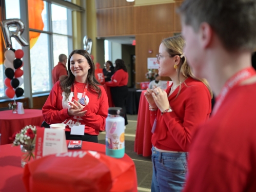 people in red Rutgers shirts smiling around table