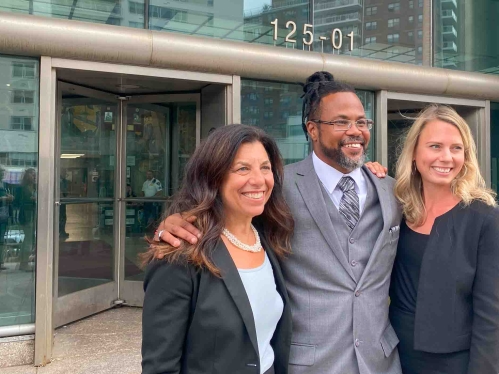 Man standing between two women outside of courthouse
