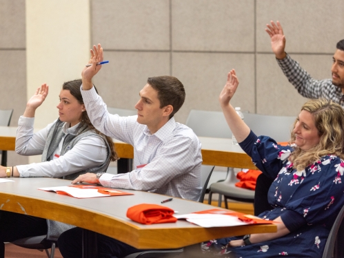 men and women raising hand in classroom