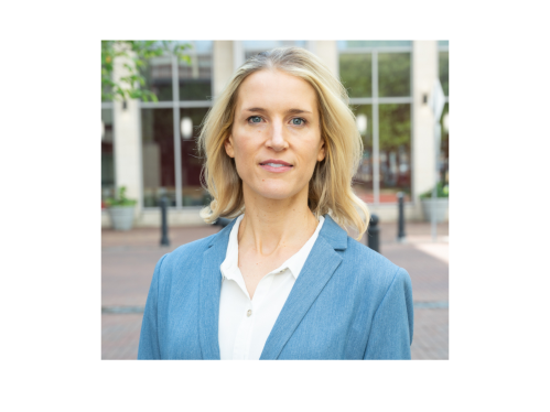 woman in white blouse and light blue blazer standing outside building