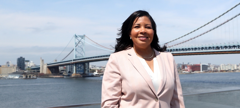Woman smiling in front of waterfront and bridge