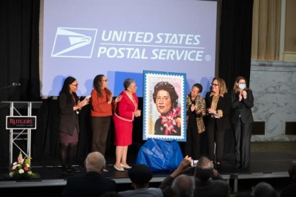 group of women standing on a stage with a giant postal stamp