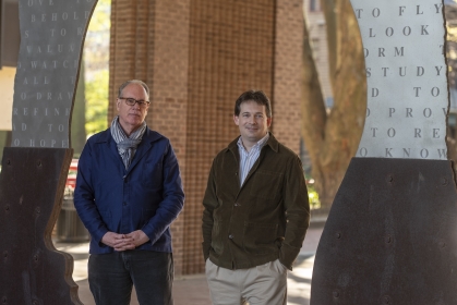 two men wearing jackets standing next to each other outside