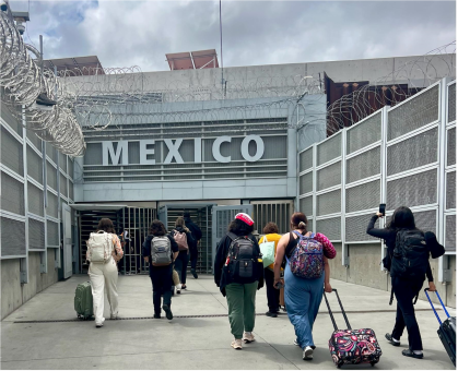 group of people walking toward building with large 'Mexico' sign