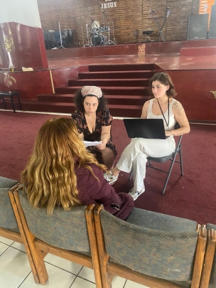 two women seated and speaking with another seated woman
