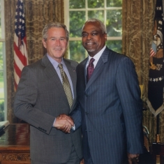 two men shaking hands with each other and posing for a photograph